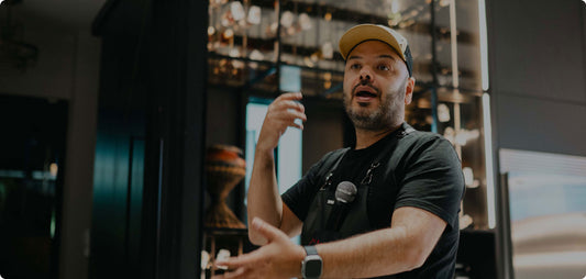 Hombre hablando con delantal y micrófono en ambiente de cocina, ideal para parrilla y asados