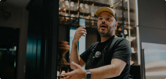 Hombre hablando con delantal y micrófono en ambiente de cocina, ideal para parrilla y asados