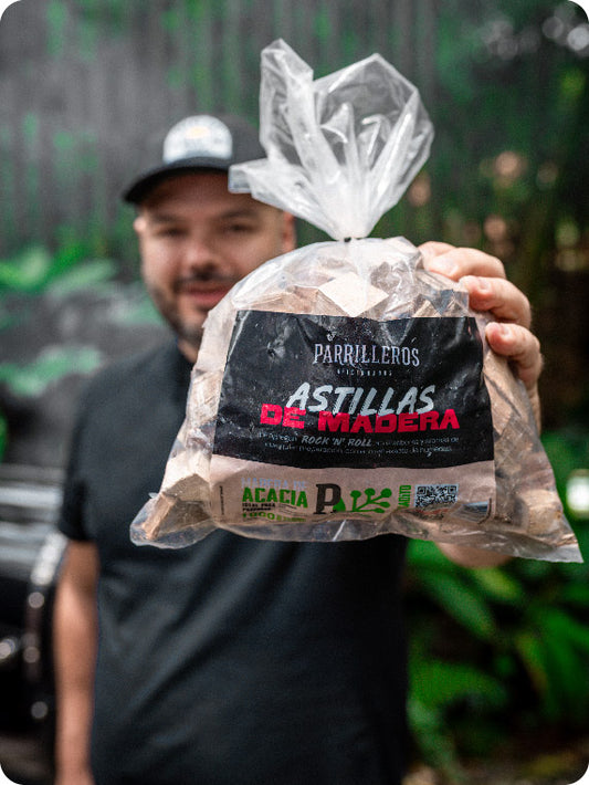 Hombre sostiene paquete de astillas de madera para ahumar, ideal para asados y bbq.